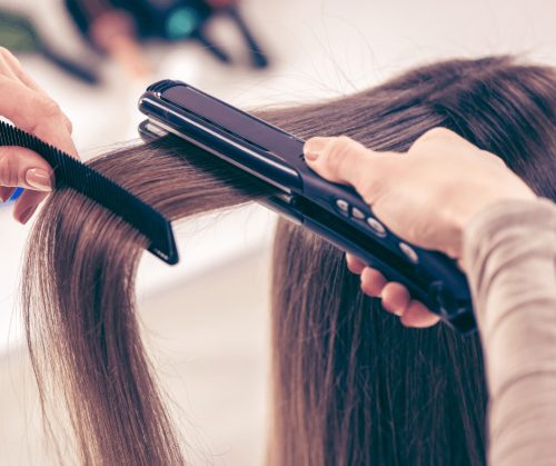 Closeup of hair being straightened with a flat iron.