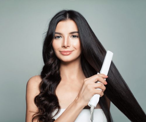 Woman straightening her hair with a flat iron.