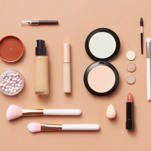 Makeup flatlay on a tan background
