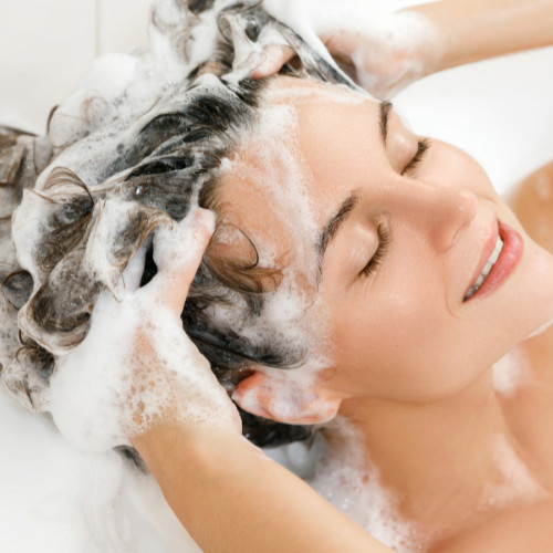 Woman washing her hair with shampoo.