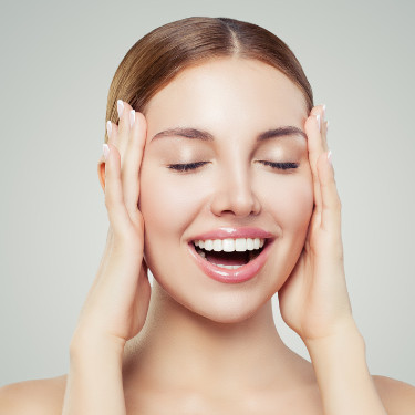 Happy woman enjoying beauty skincare routine and touching the skin on her face.