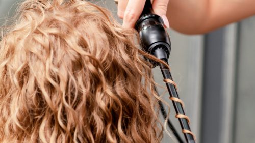 Hair being curled by a curling iron.