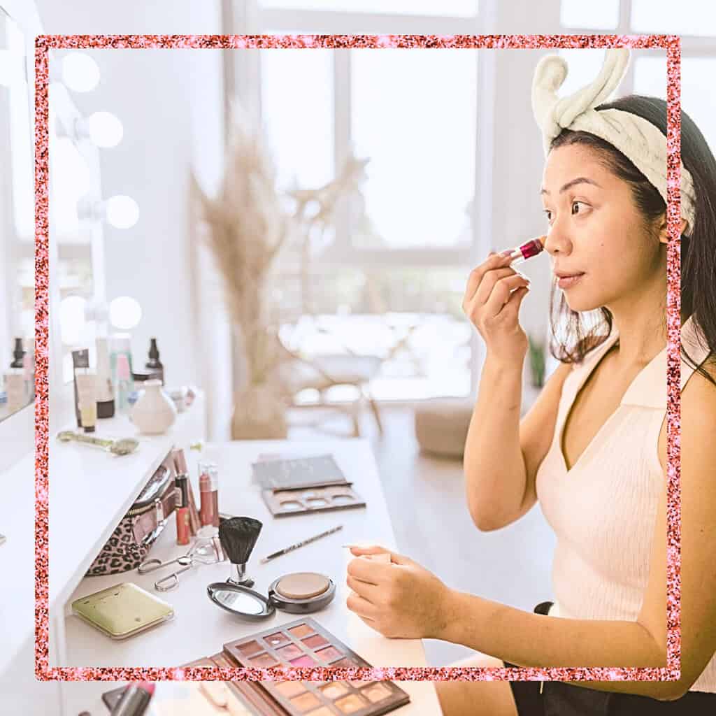 Beautiful woman doing her makeup on white vanity.